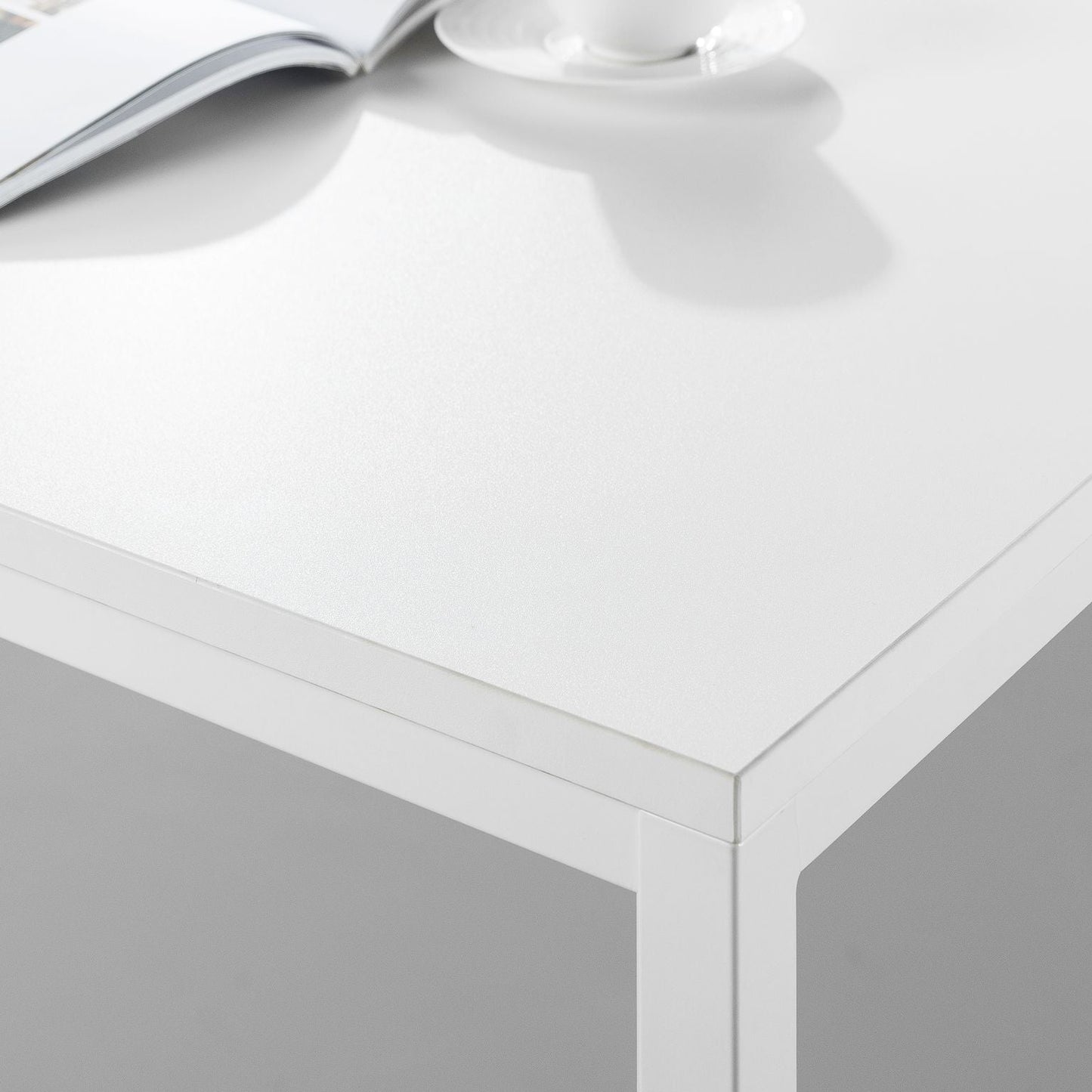 Modern white office desk with metal frame, open book and coffee cup on top