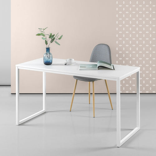 Minimalist white office desk with metal legs, grey chair, blue vase, and open magazine in modern workspace