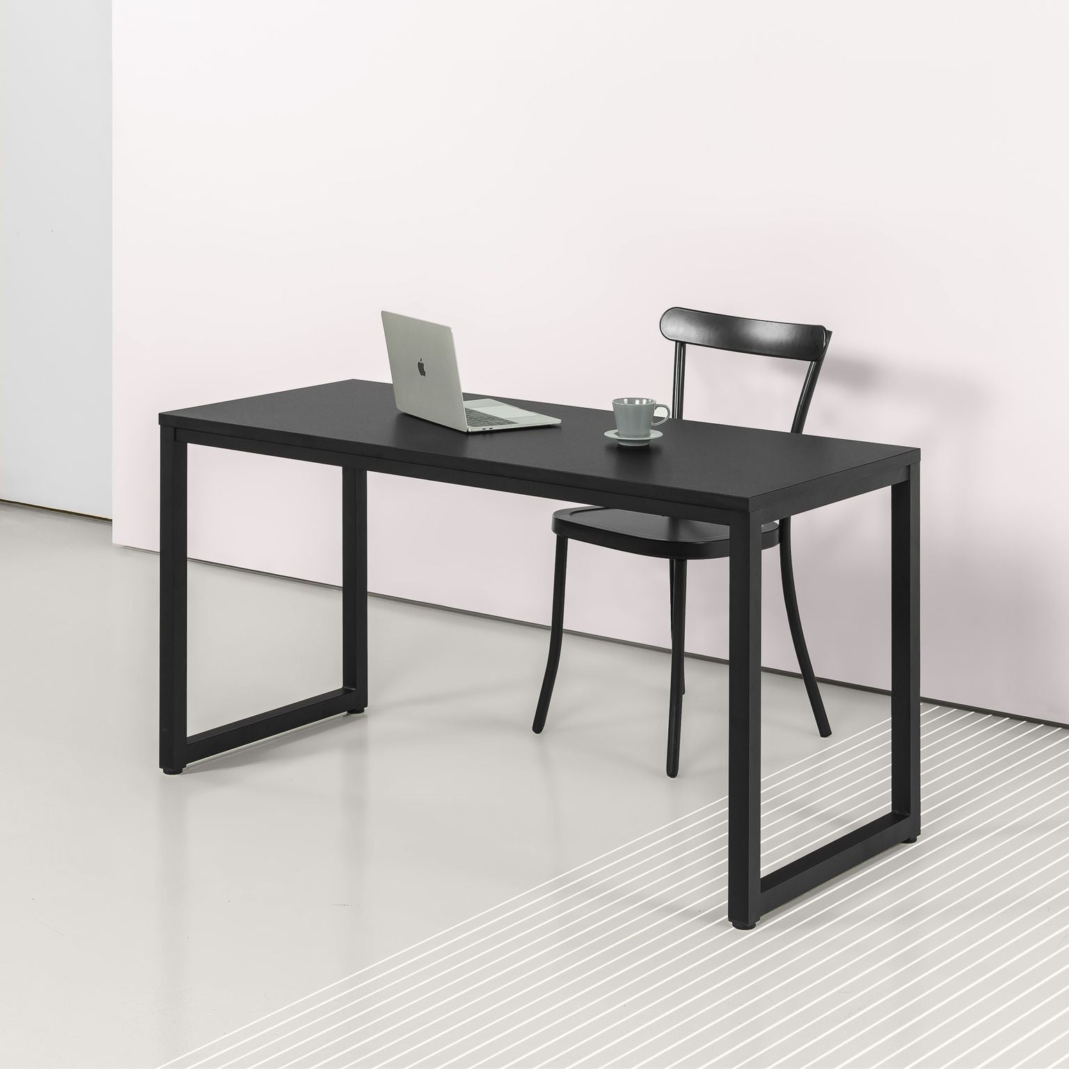 Modern black office desk with metal frame and laptop in minimalist workspace setting