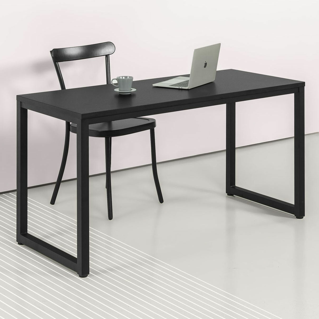 Modern black office desk with minimalist chair, laptop, and cup in a bright workspace