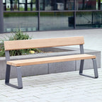  Wooden bench with metal legs on a paved area with a glass building in the background