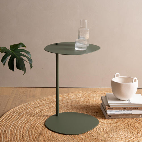 Modern green side table on woven rug with minimalist decor and glassware