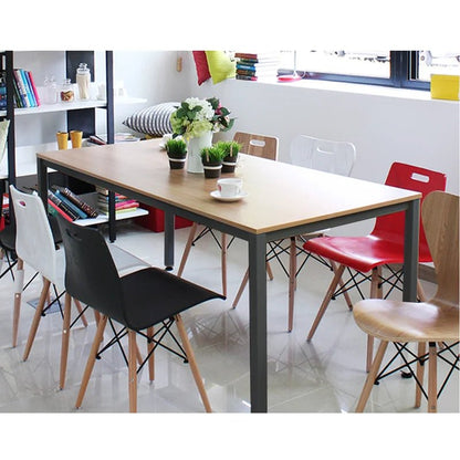 Modern rectangular wooden desk with metal legs, surrounded by colorful dining chairs in a bright room.
