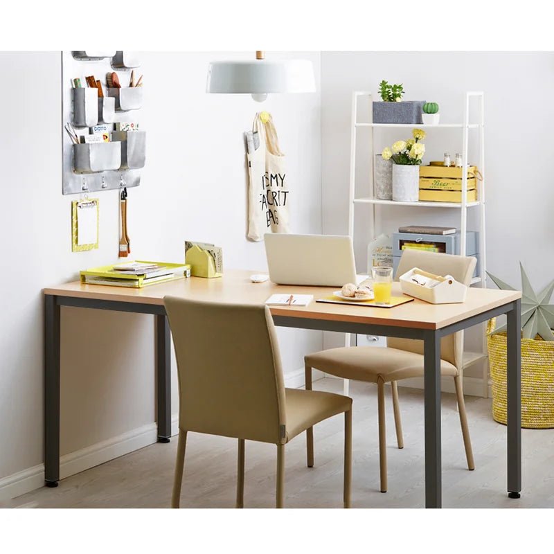 Modern wooden desk with metal legs in a bright home office, two chairs, laptop, shelf, and decor.