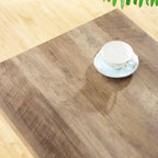 Wood desk with light brown finish and a white teacup on a saucer on top