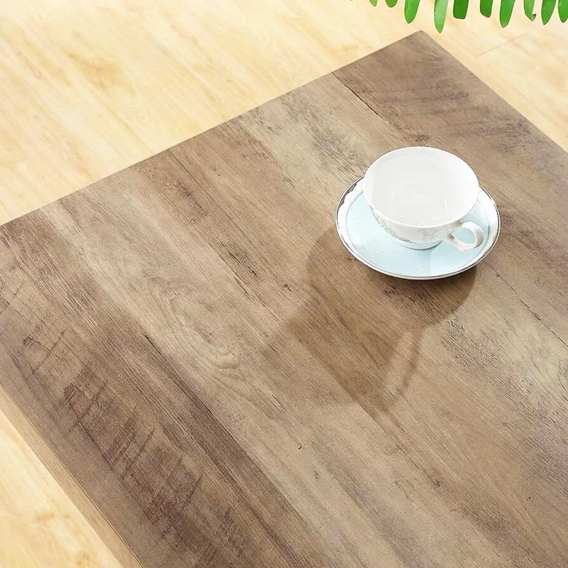 Wood desk with light brown finish and a white teacup on a saucer on top