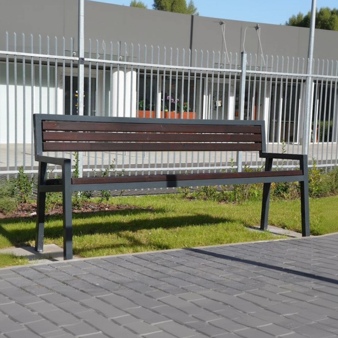 Outdoor modern park bench with metal frame and wooden slats on grass near sidewalk