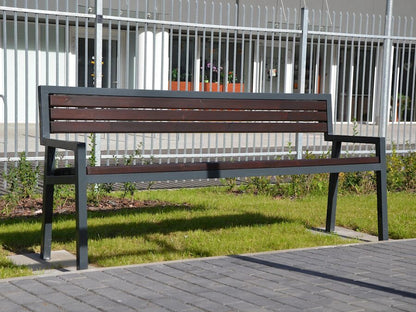 Outdoor modern park bench with metal frame and wooden slats on grass near sidewalk