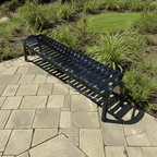 Black metal backless bench on stone paving in an outdoor garden setting