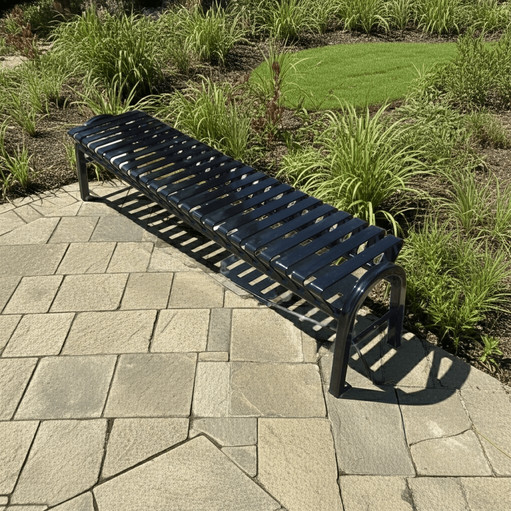 Black metal backless bench on stone paving in an outdoor garden setting