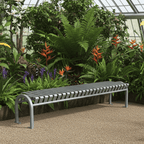 Heavy-duty metal backless bench in a garden setting with lush green plants and flowers