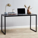 Modern black office desk with laptop, books, lamp, and decorative vase in a minimalist room