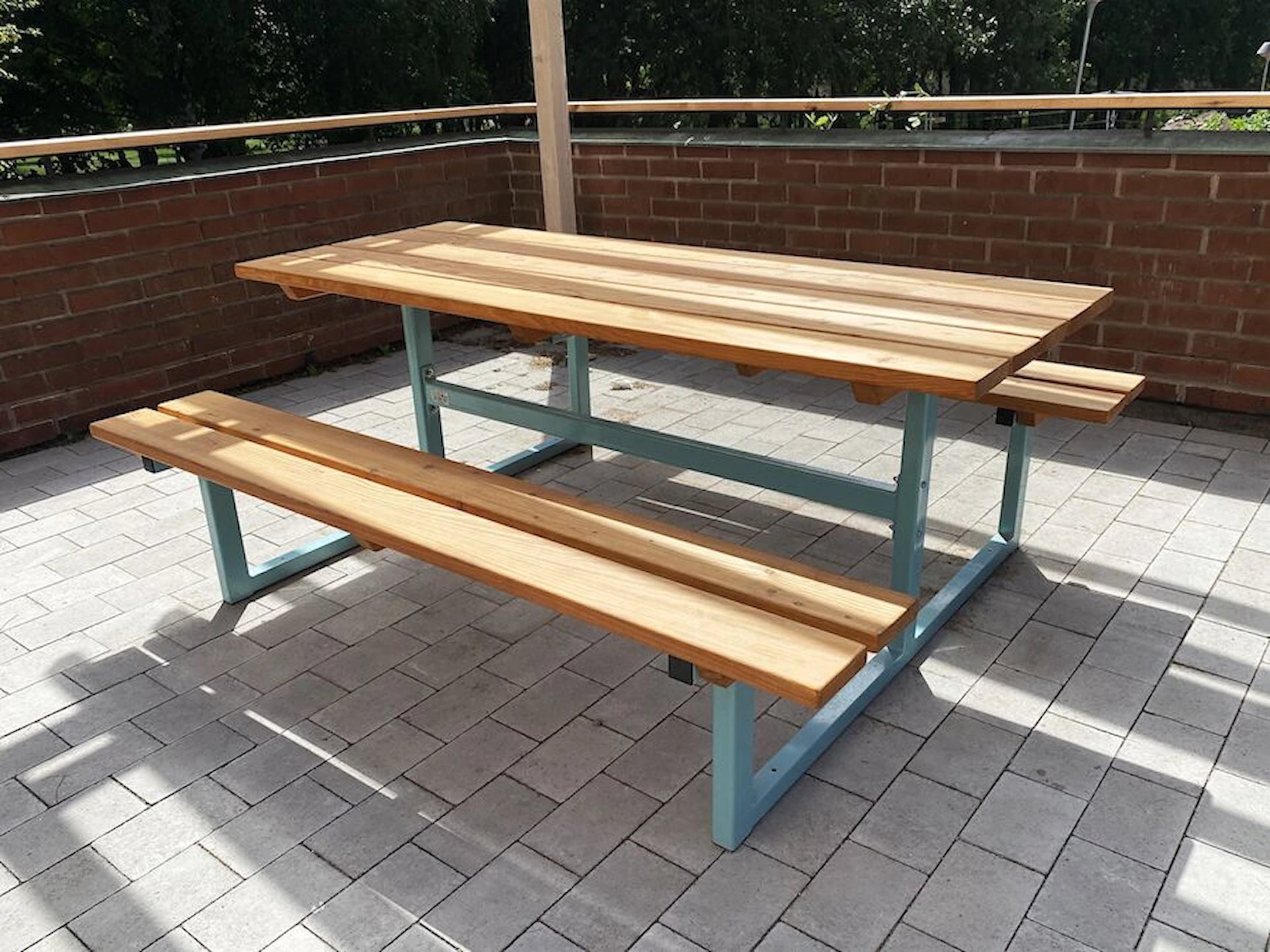Modern outdoor wooden bench and table set with light blue metal frame on a patio