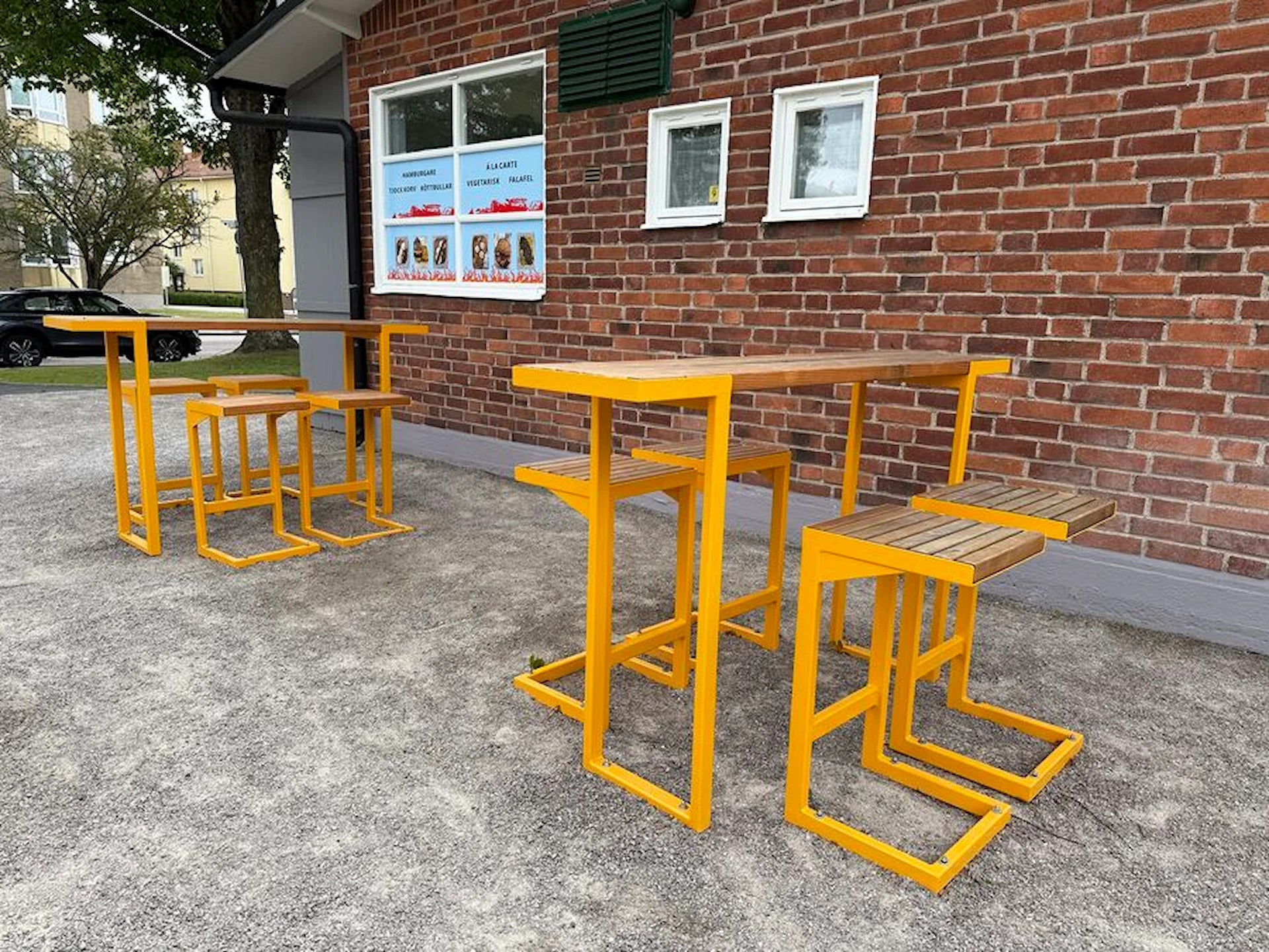 Modern outdoor bar table sets with bright yellow metal frames and wooden seats on patio
