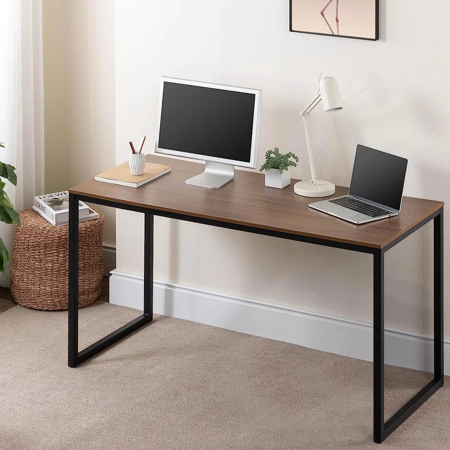 Modern wood and metal desk with computer monitor, laptop, lamp, and decor in a home office