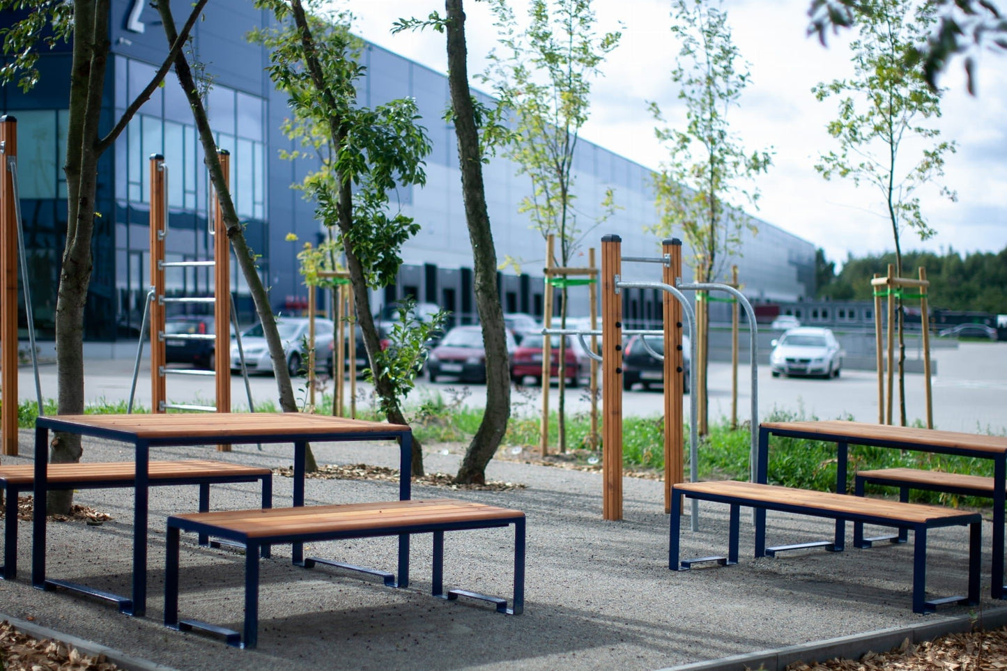 Outdoor public backless benches with metal frames and wood seats in a modern urban park setting