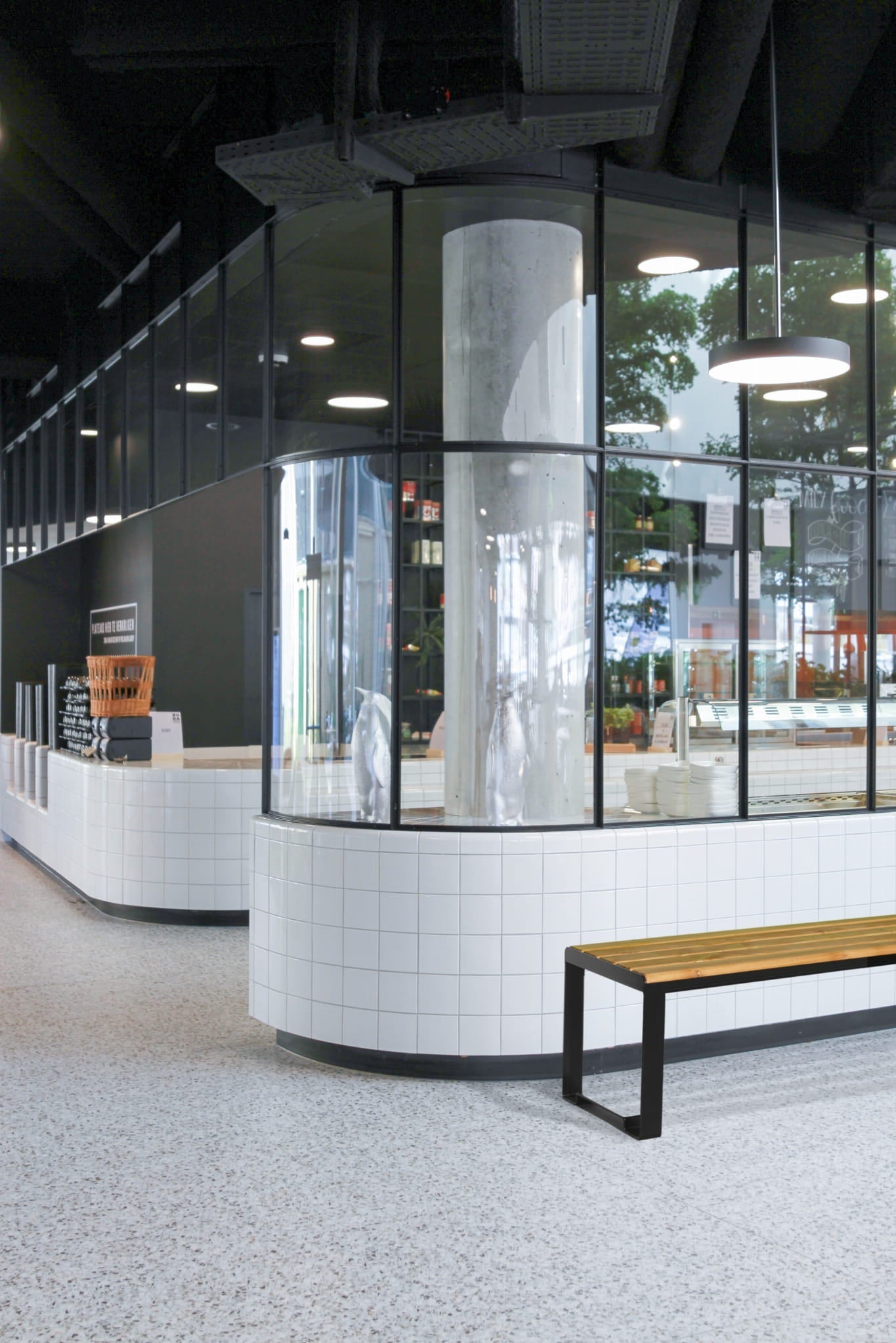 Backless three-seater wooden bench with metal legs in a modern public indoor space