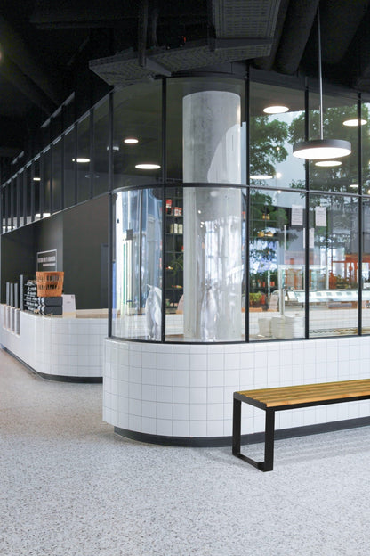 Backless three-seater wooden bench with metal legs in a modern public indoor space