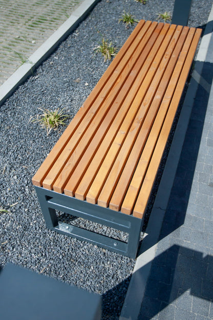 Modern outdoor backless wooden bench with black metal frame on gravel landscaping