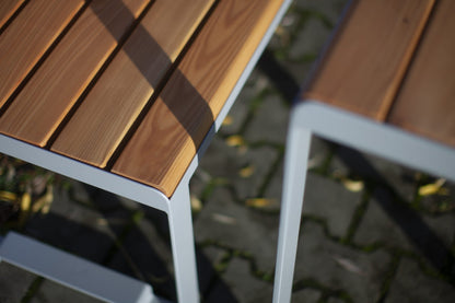Modern outdoor backless bench with wooden slats and metal frame on stone pavement