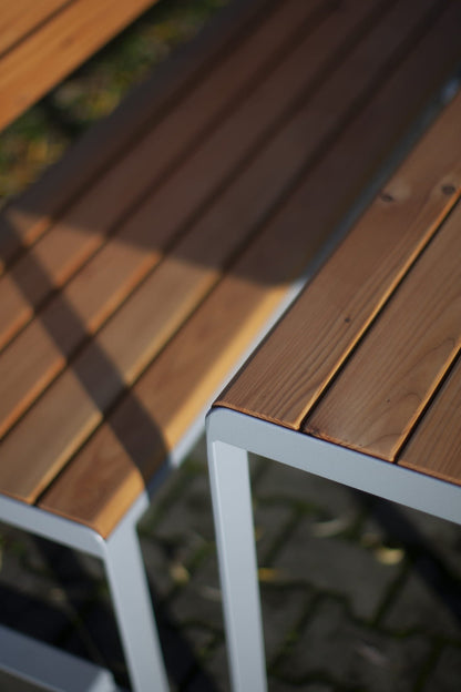 Close-up of slatted wood and metal 3-seater bench with backrest, outdoor setting