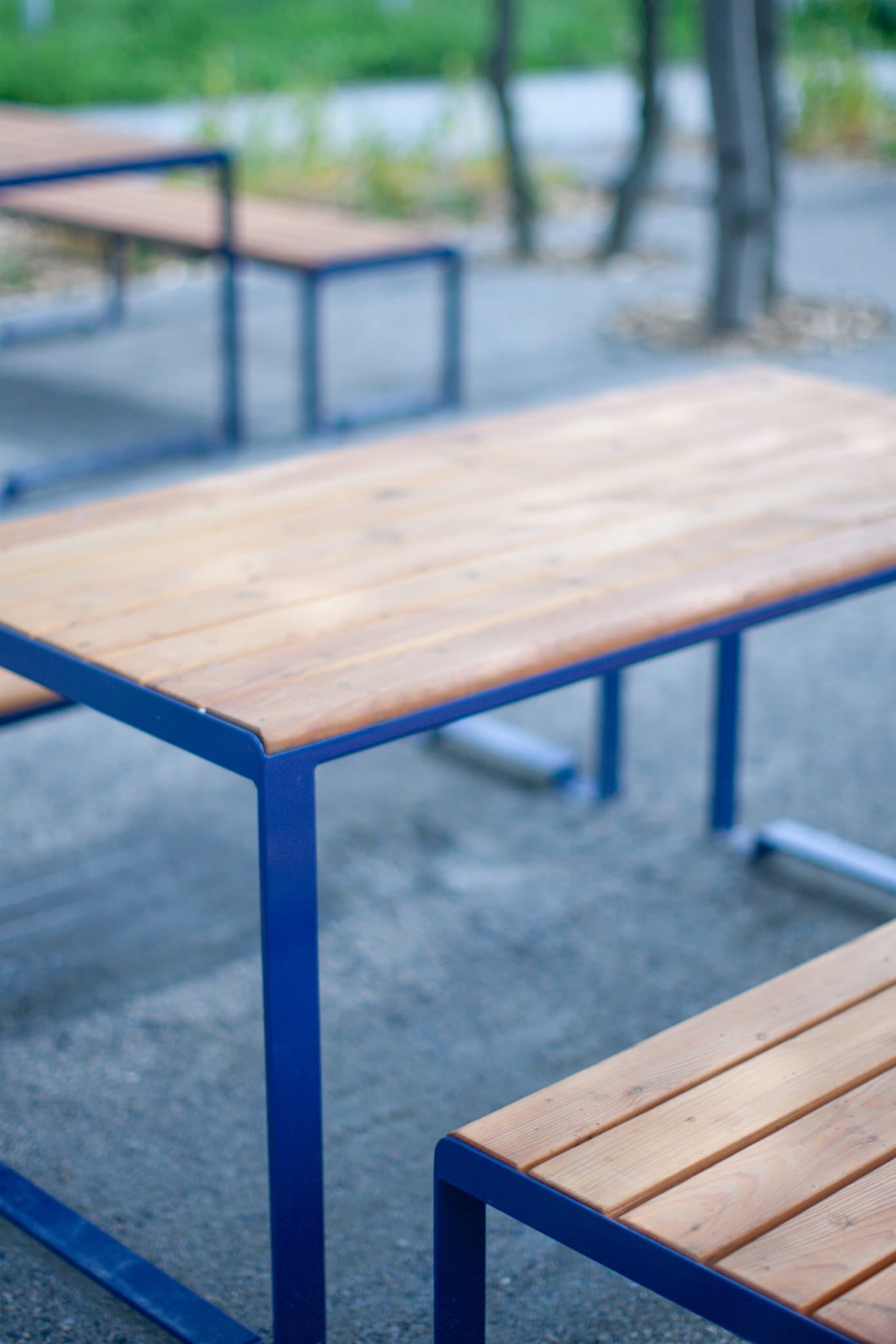 Modern outdoor bench and table set with wooden slats and blue metal frame on pavement