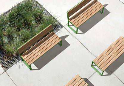 Modern outdoor wooden benches with green metal frames on a concrete patio near grassy planter