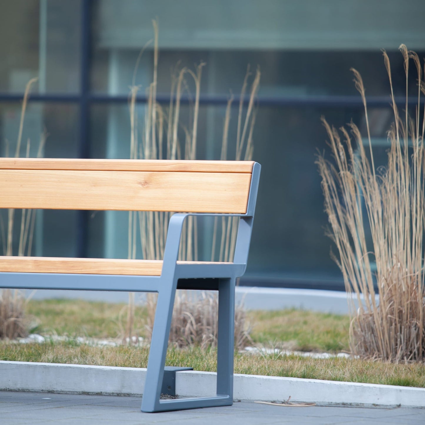 Modern 3-seater public bench with wooden backrest and metal armrest in outdoor setting