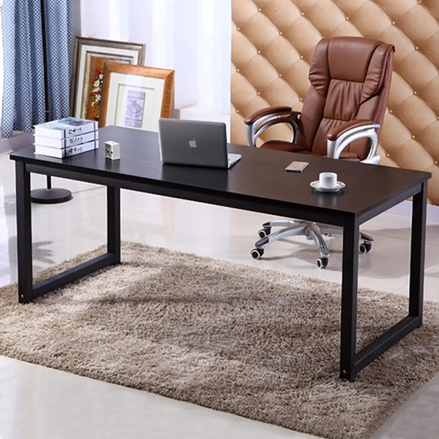 Modern black home office desk with metal frame, laptop, books, and brown chair on rug