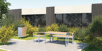 Modern outdoor table set with matching benches and metal frame, placed on patio by shrubs