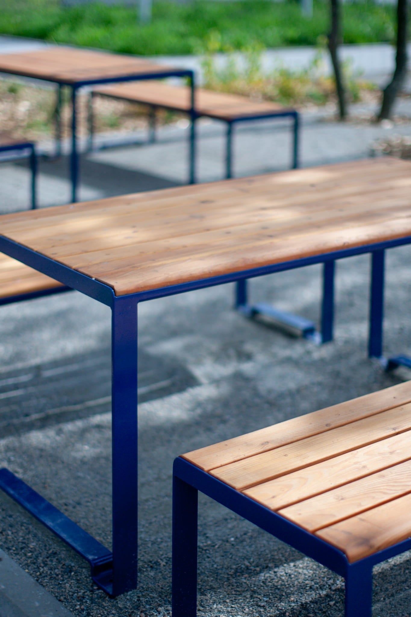 Outdoor wooden table with blue metal frame and matching benches on patio