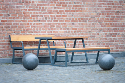 Modern outdoor table with matching benches and metal frame, set against a brick wall.