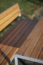 Outdoor wooden slat table and bench with metal frame on grass patio