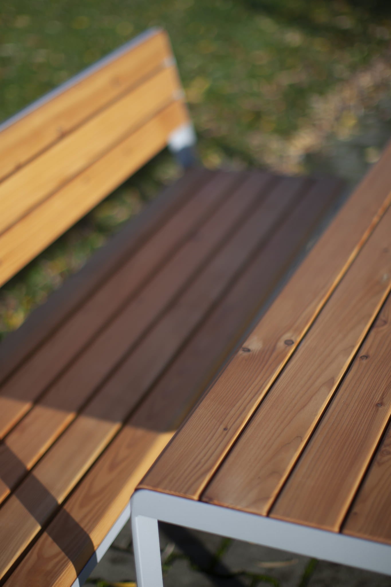 Outdoor wooden slat table and bench with metal frame on grass patio