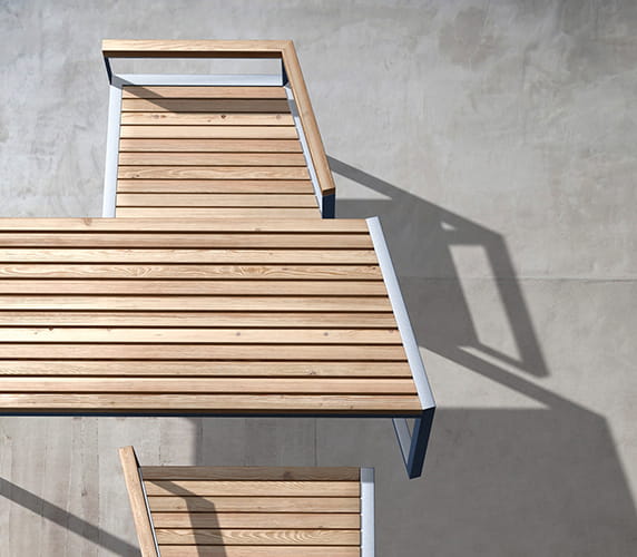 Modern outdoor wooden table with metal frame and matching chair on concrete patio