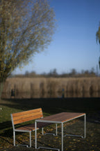 Modern outdoor table and bench set with wood and metal, placed in a natural park setting