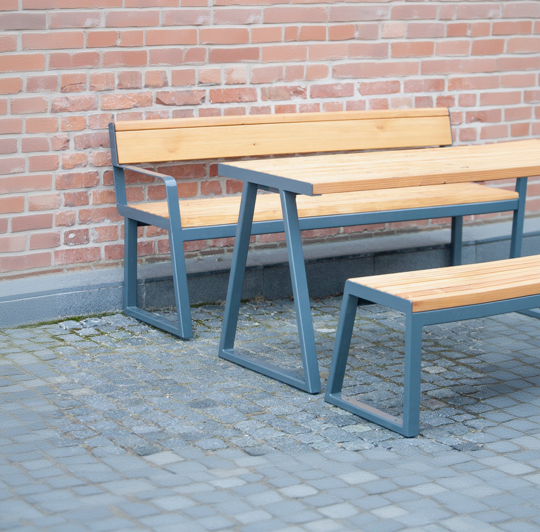 Outdoor wooden table with metal frame, matching bench and seat, set against brick wall