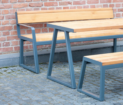 Outdoor wooden table with metal frame, matching bench and seat, set against brick wall