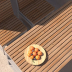 Outdoor wooden table with matching benches and a fruit plate in natural sunlight