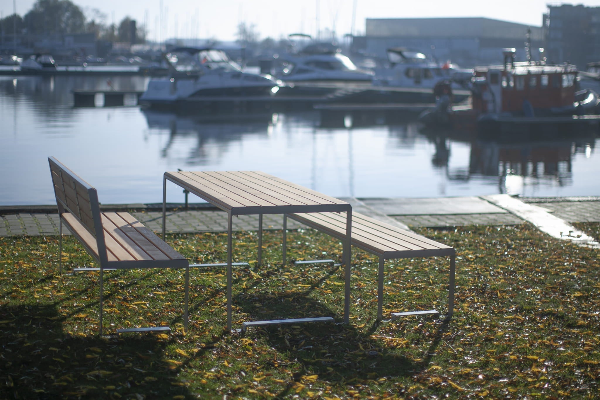 Modern outdoor wooden table with matching benches by a marina, seats 6 to 8 people