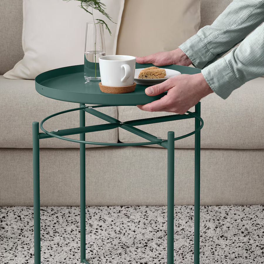 Modern green round tray table with coffee cup and vase in living room setting