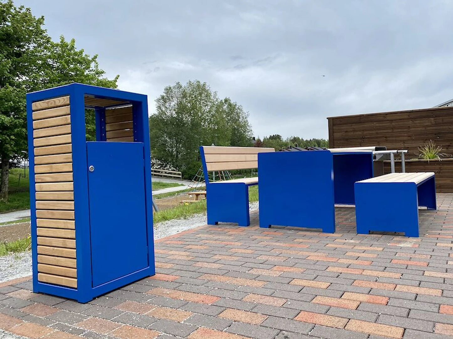 Modern blue and wood outdoor wastebasket with matching benches and tables on patio