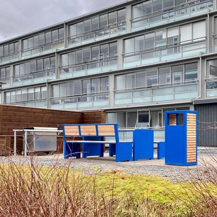 Modern blue and wood outdoor wastebasket near matching benches by apartment building