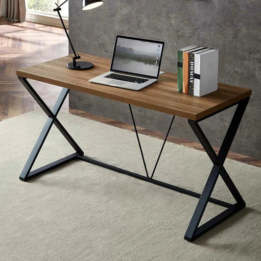 Modern steel and wood desk with X-frame legs, laptop, books, and lamp in a home office