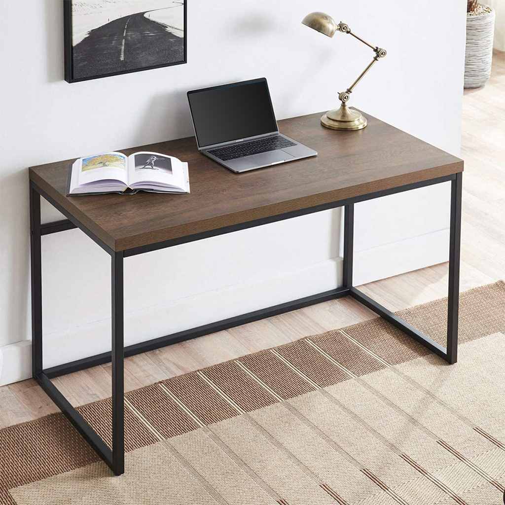 Modern brown and black office desk with metal frame, open laptop, book, and desk lamp