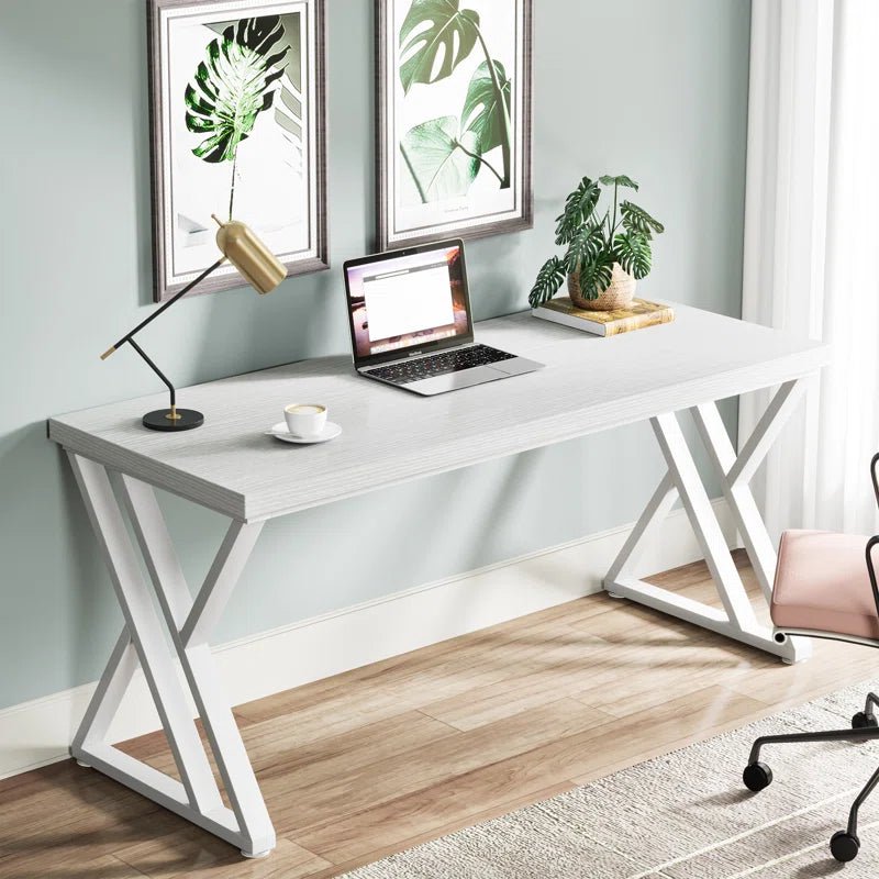 Modern white computer desk with metal legs in a home office, featuring a laptop, desk lamp, and potted plant.