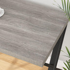 Modern grey wood computer desk with black metal legs, shown in a home interior setting